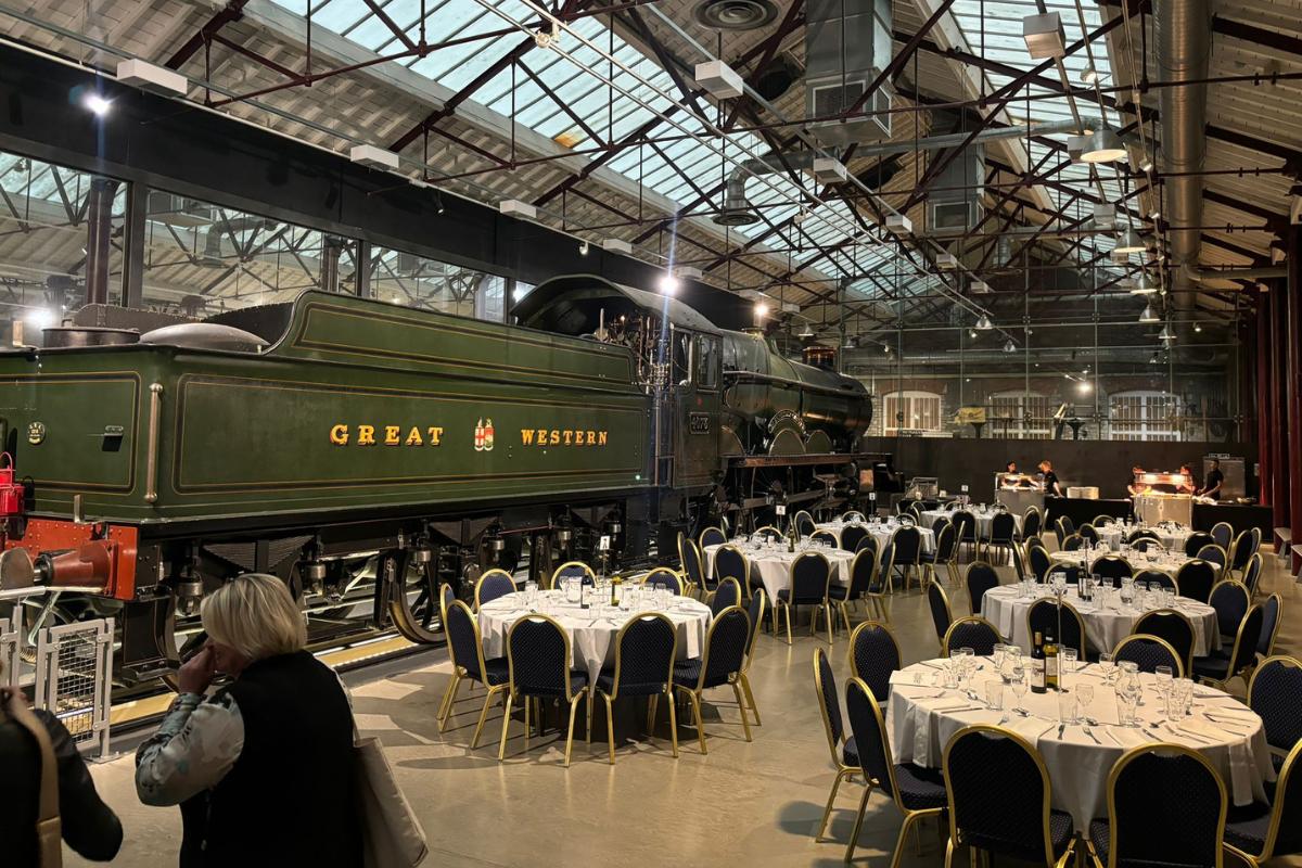 Tables set up for dinner next to an old train in a railway museum