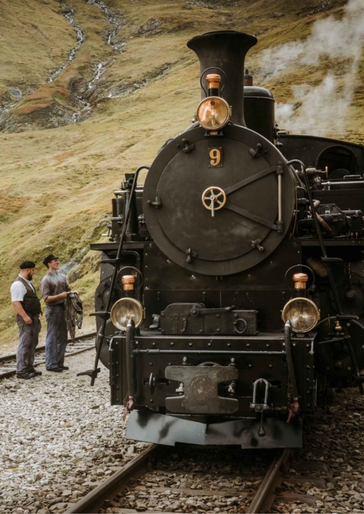Furka Cogwheel Railway locomotive with railway workers in Alpine valley, heritage steam railway Switzerland